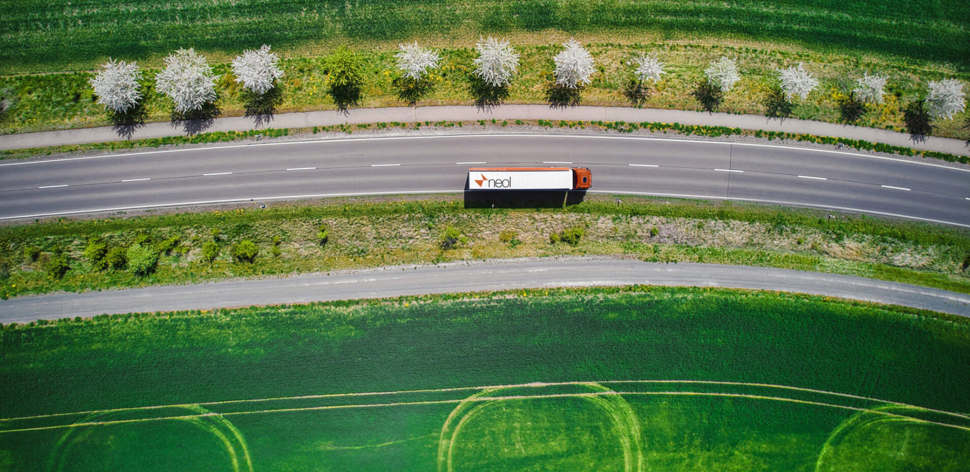 Road through fields with a NEOL branded truck